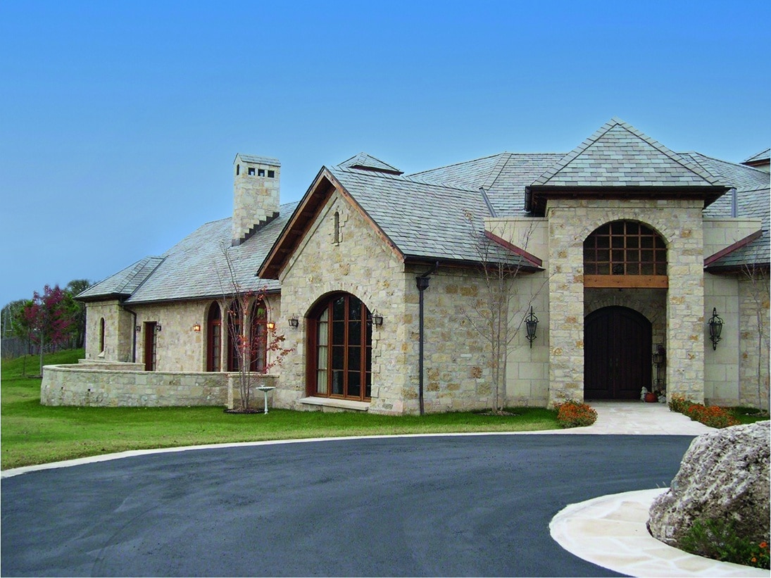 An exterior view of a stone mansion with wood windows.