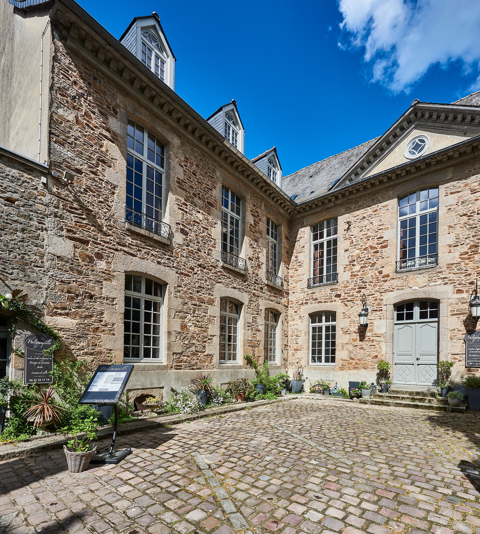 An exterior view of a three-story French country house and the main entry.