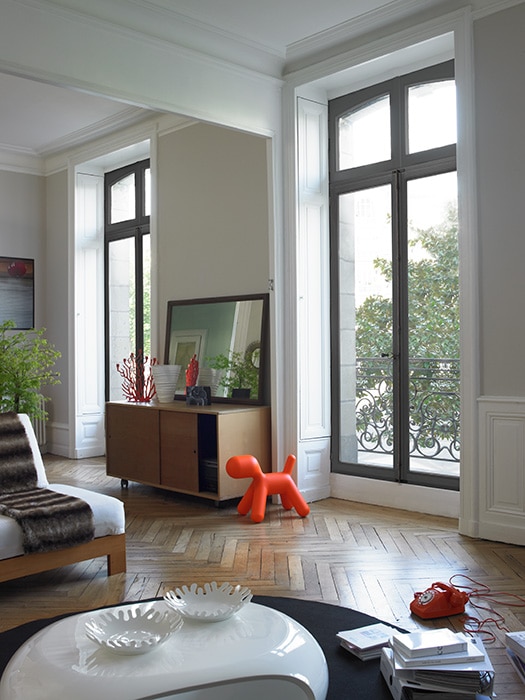 The interior view of a living room showcasing floor to ceiling wood windows and doors.