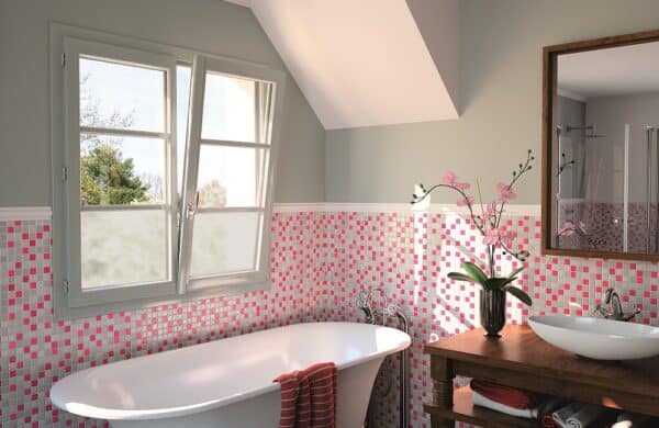 A pink, white, and gray tile bathroom with a slightly opened wood window.