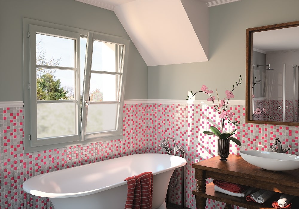 A pink, white, and gray tile bathroom with a slightly opened wood window.